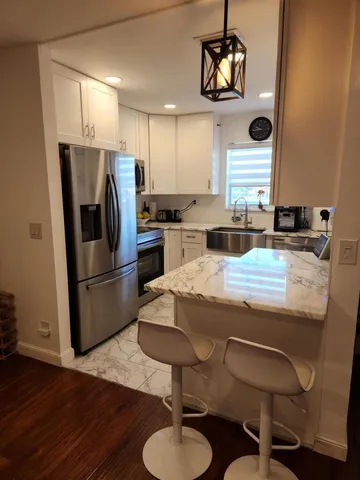 a kitchen with granite countertop a stove a refrigerator and a dining table with wooden floor