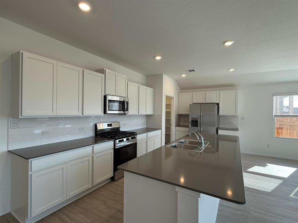 263 Magalia Lane Kyle, TX 78640 - Photo 15 of 37 a kitchen with stainless steel appliances granite countertop a sink a stove and a refrigerator