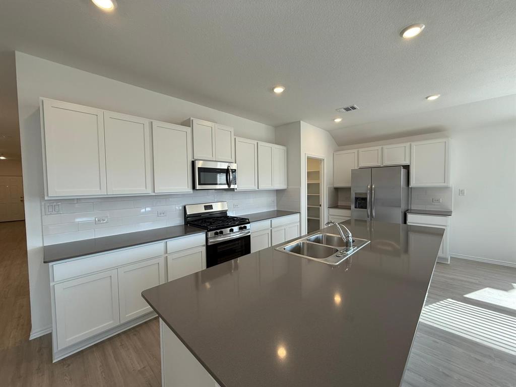 263 Magalia Lane Kyle, TX 78640 - Photo 16 of 37 a kitchen with stainless steel appliances granite countertop a sink refrigerator stove and microwave