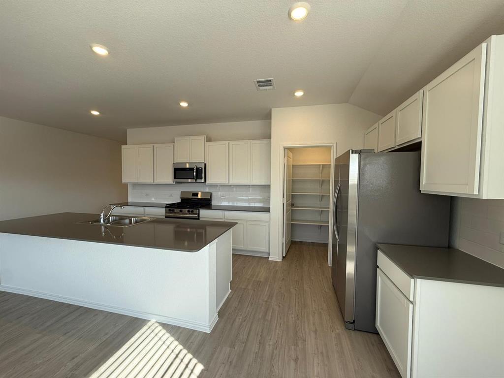 263 Magalia Lane Kyle, TX 78640 - Photo 19 of 37 a kitchen with stainless steel appliances granite countertop a refrigerator a oven a sink a stove and white cabinets with wooden floor