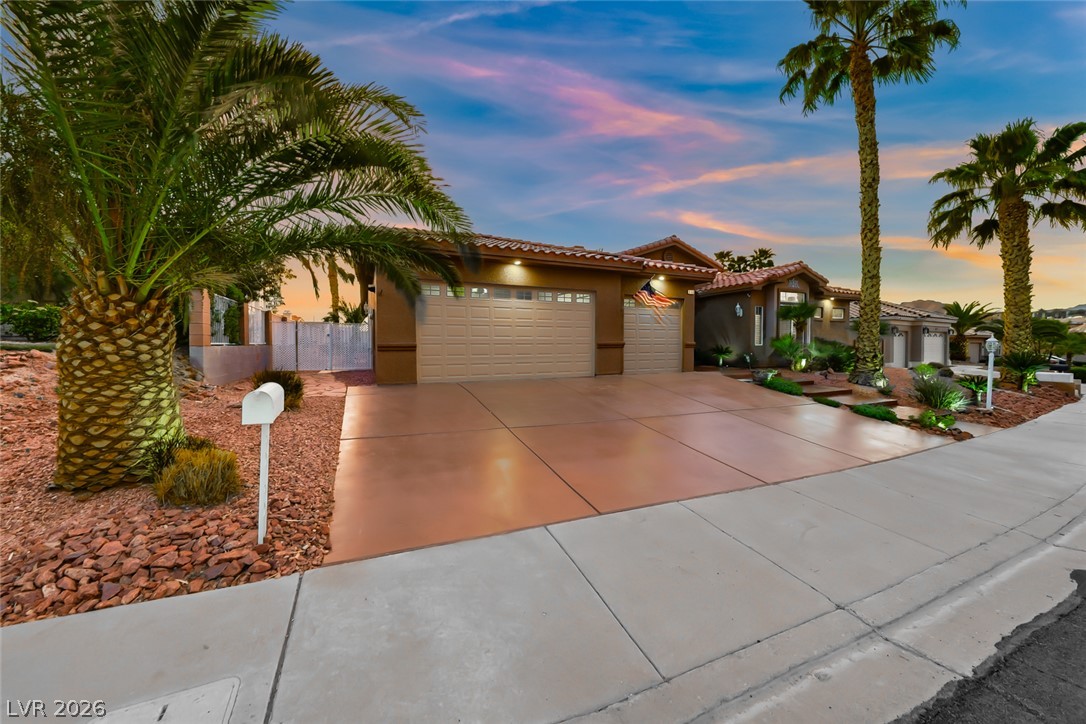 1104 Norellat Road Henderson, NV 89011 - Photo 2 of 52 Mature palms frame a spacious concrete driveway leading to the integrated multi-car garage.