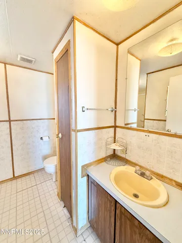 a bathroom with a granite countertop sink a toilet a mirror and shower