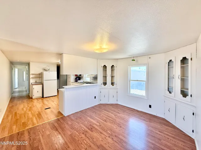 a large white kitchen with granite countertop a sink and dishwasher with wooden floor