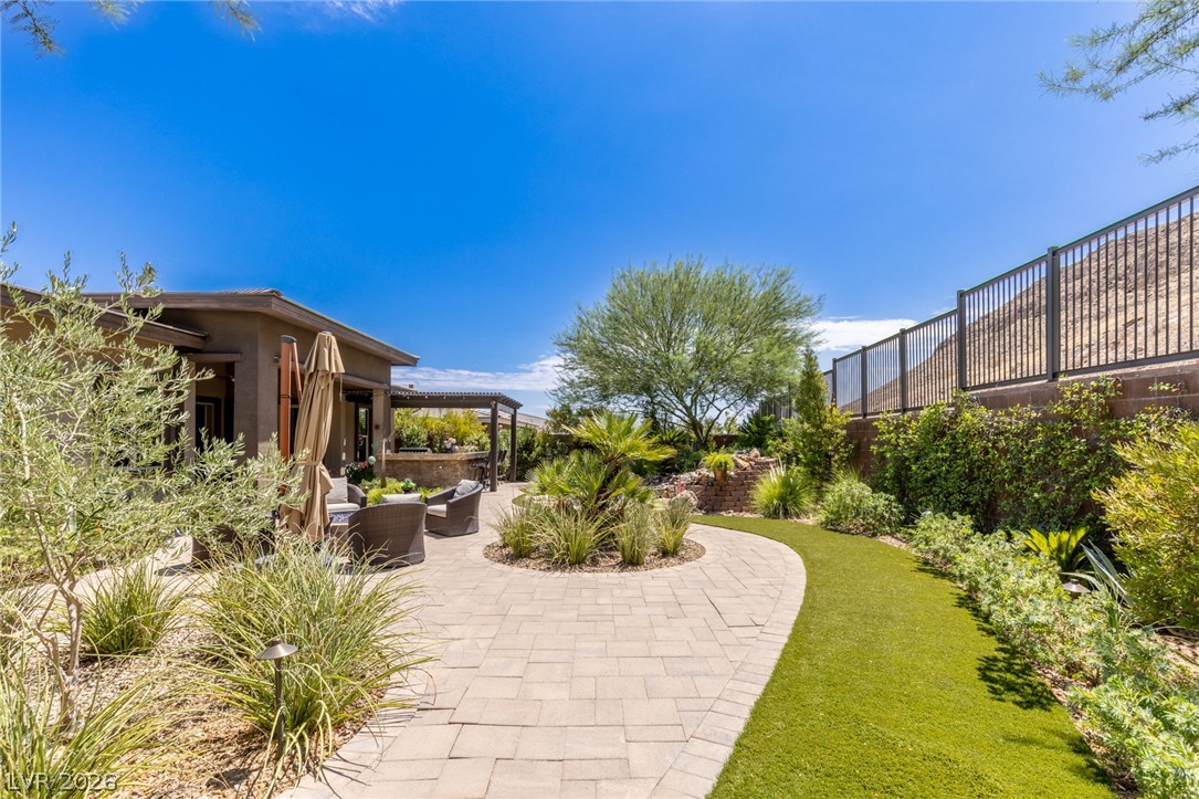 10167 Copper Edge Road Las Vegas, NV 89148 - Photo 32 of 45 An inviting backyard oasis offers a paved patio, lush landscaping, and tranquil outdoor living spaces.