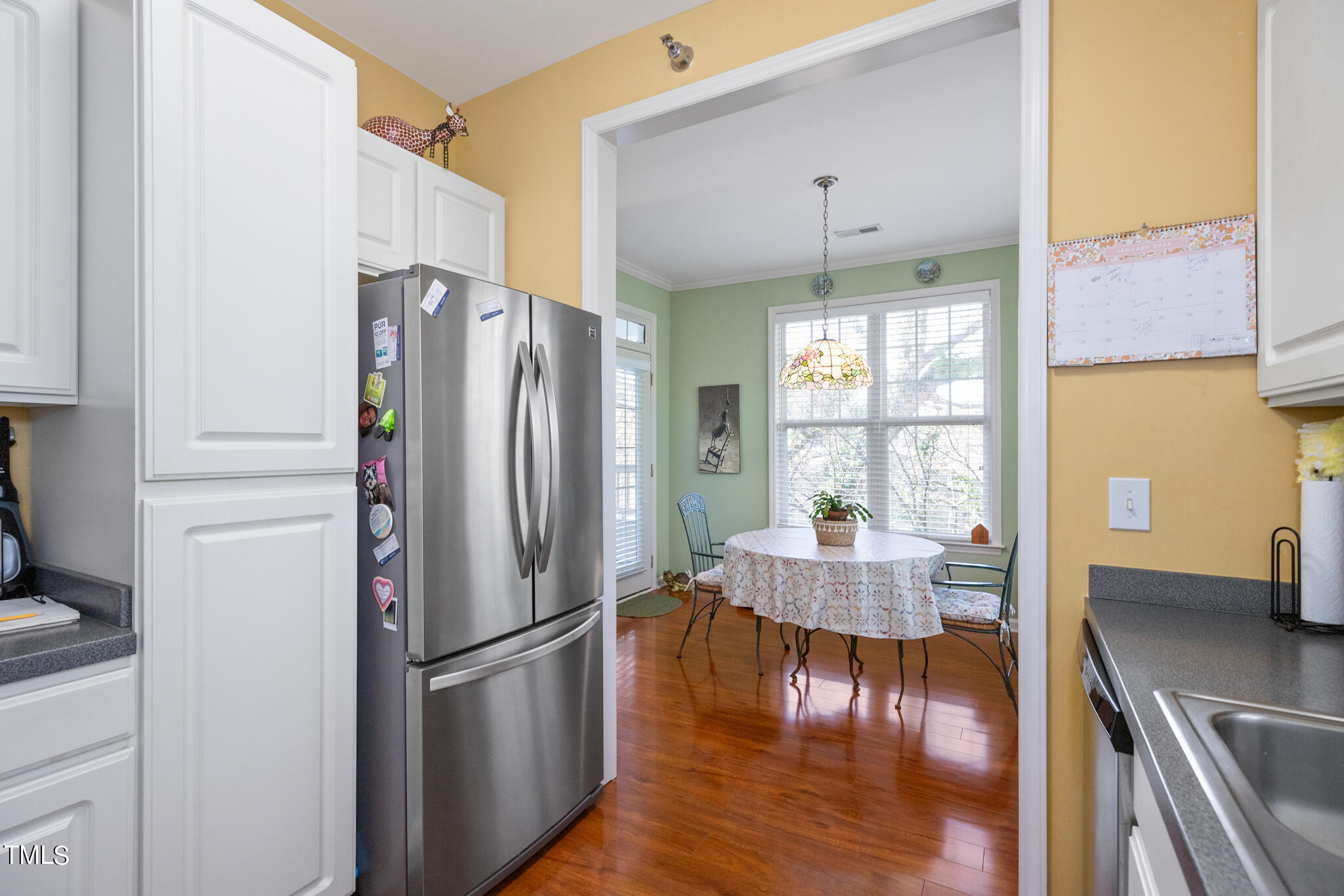 1700 Tiffany Bay Court, Unit 303 Raleigh, NC 27609 - Photo 17 of 30 a kitchen with stainless steel appliances granite countertop a refrigerator a stove and a dining table with wooden floor