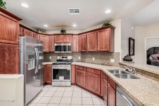 a kitchen with stainless steel appliances granite countertop a sink stove refrigerator and cabinets