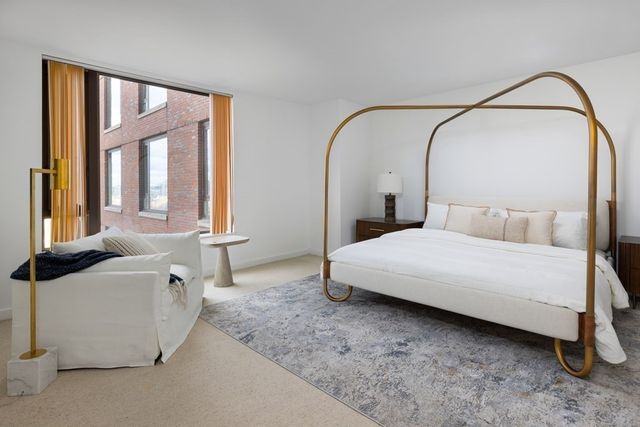 a bedroom with a bed and a large mirror next to a window