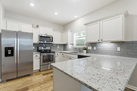 a kitchen with stainless steel appliances granite countertop a sink a stove a refrigerator a microwave and cabinets