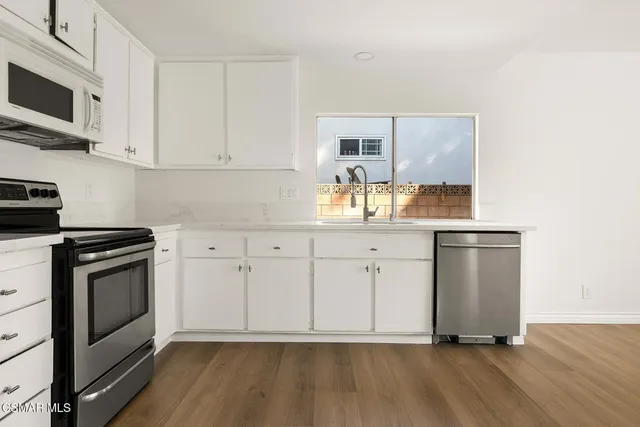 a kitchen with stainless steel appliances granite countertop a sink a stove and cabinets