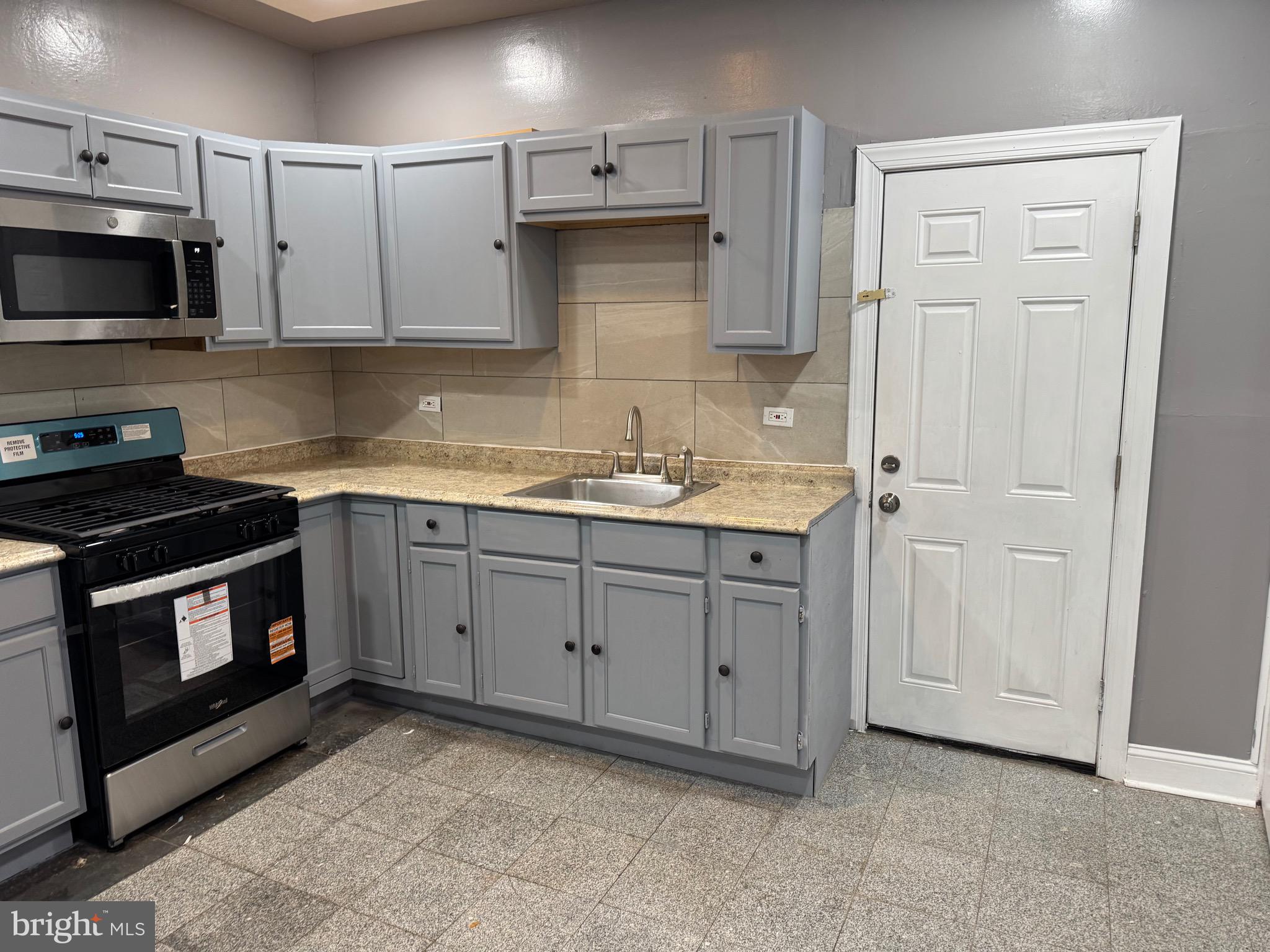 132 Walnut Street Colwyn, PA 19023 - Photo 5 of 43 a kitchen with white cabinets stainless steel appliances and sink