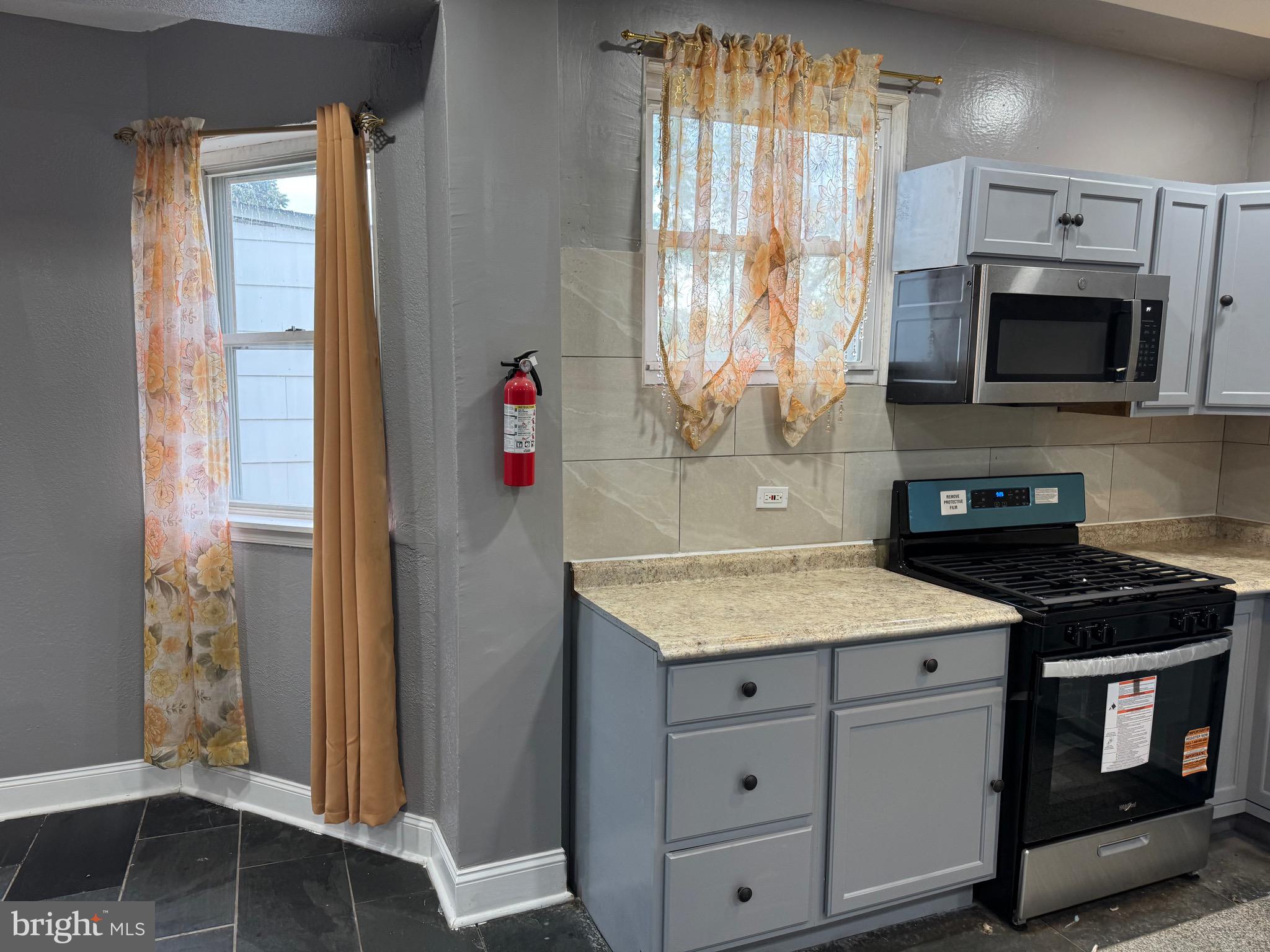 132 Walnut Street Colwyn, PA 19023 - Photo 8 of 43 a kitchen with stainless steel appliances granite countertop a stove a sink and a microwave