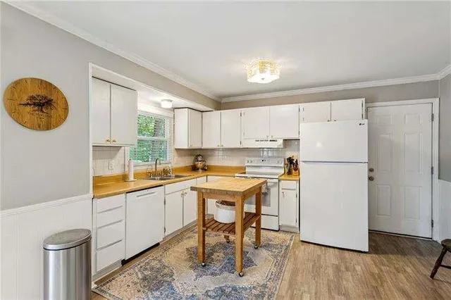 a kitchen with a refrigerator a sink and dishwasher with wooden floor