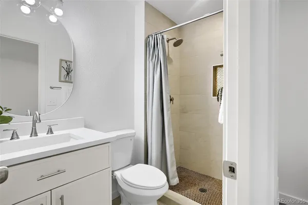 a bathroom with a sink a mirror a toilet and shower