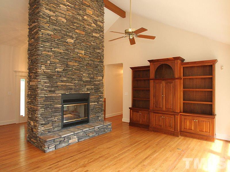 8216 Inverstone Lane Raleigh, NC 27606 - Photo 4 of 25 Floor-to-ceiling stone gas log fireplace, built in solid walnut cabinets, cathedral ceiling, wall of windows let in lots of light.