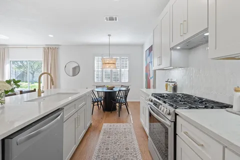 a kitchen with granite countertop a sink stove and cabinets