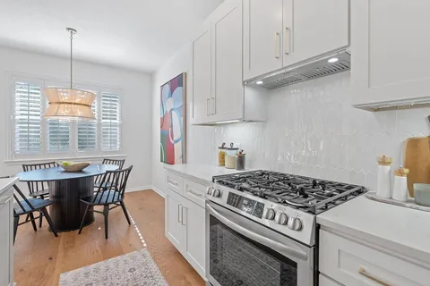 a kitchen with a stove a window and cabinetry