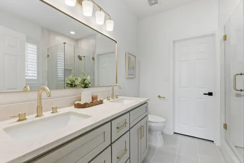 a bathroom with a sink a toilet a large mirror and shower