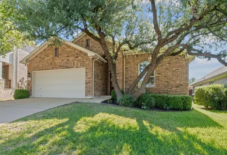 a view of a house with a small yard and a large tree