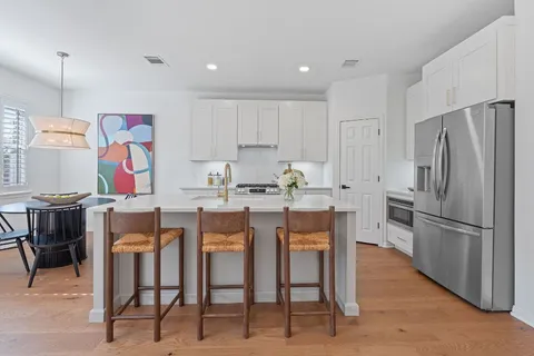 a kitchen with granite countertop stainless steel appliances a table and chairs in it