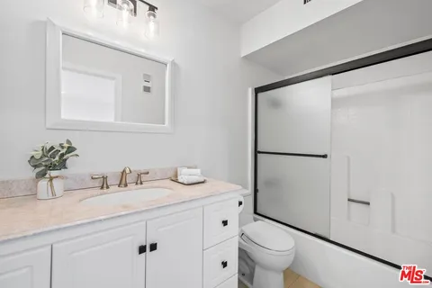 a bathroom with a granite countertop sink a toilet and a mirror