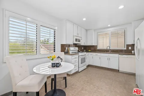 a kitchen with stainless steel appliances granite countertop a stove a sink a microwave a dining table and chairs