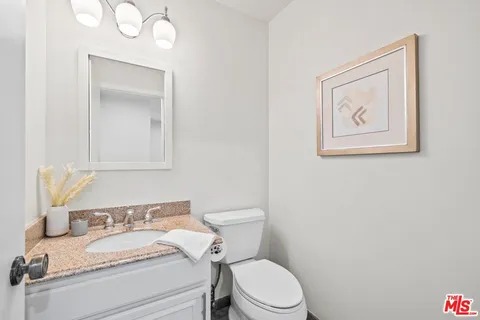 a bathroom with a granite countertop sink mirror vanity and toilet