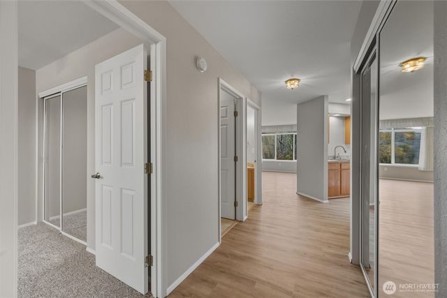 a view of a hallway with wooden floor and a kitchen