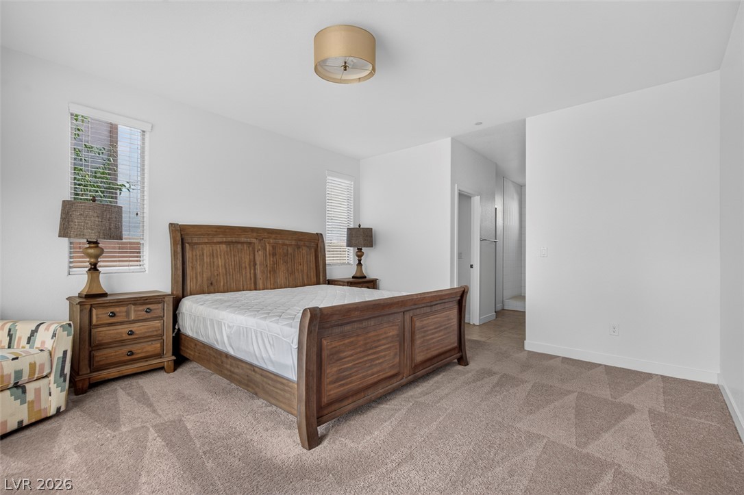 1100 East Sunset Road Henderson, NV 89011 - Photo 16 of 58 Well-lit primary bedroom features soft carpet flooring, blinds, and a private ensuite bathroom entrance.