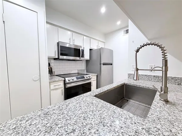 a kitchen with stainless steel appliances a refrigerator a stove a microwave and a sink