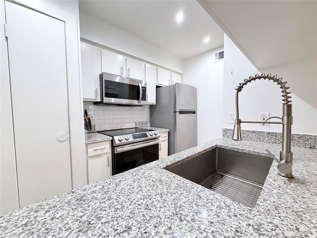 a kitchen with stainless steel appliances a refrigerator a stove a microwave and a sink