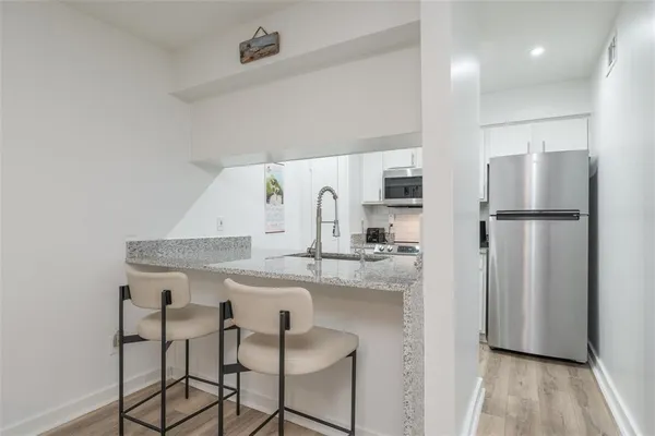 a kitchen with kitchen island a counter top space a refrigerator and a sink