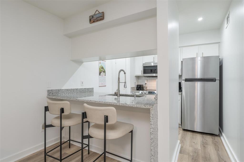 4837 Cedar Springs Road, Unit 110 Dallas, TX 75219 - Photo 2 of 21 a kitchen with kitchen island a counter top space a refrigerator and a sink
