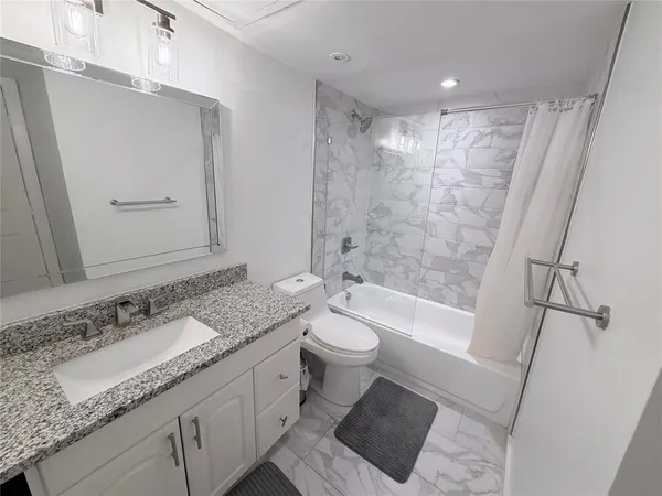a bathroom with a granite countertop sink toilet and shower