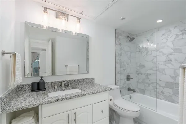 a bathroom with a granite countertop sink a toilet and bathtub