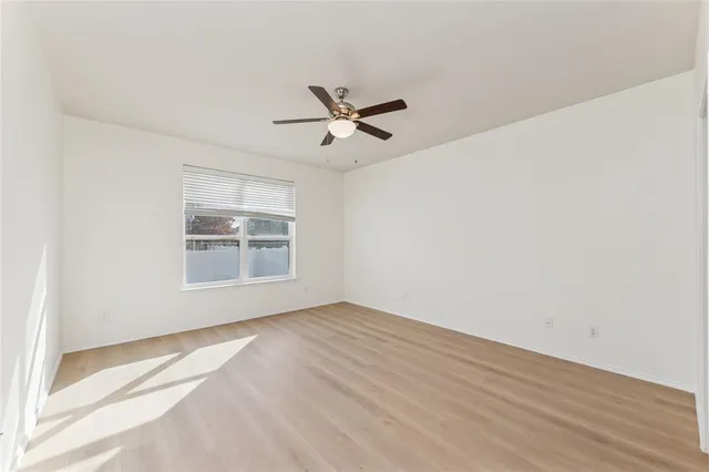a view of empty room with wooden floor and ceiling fan