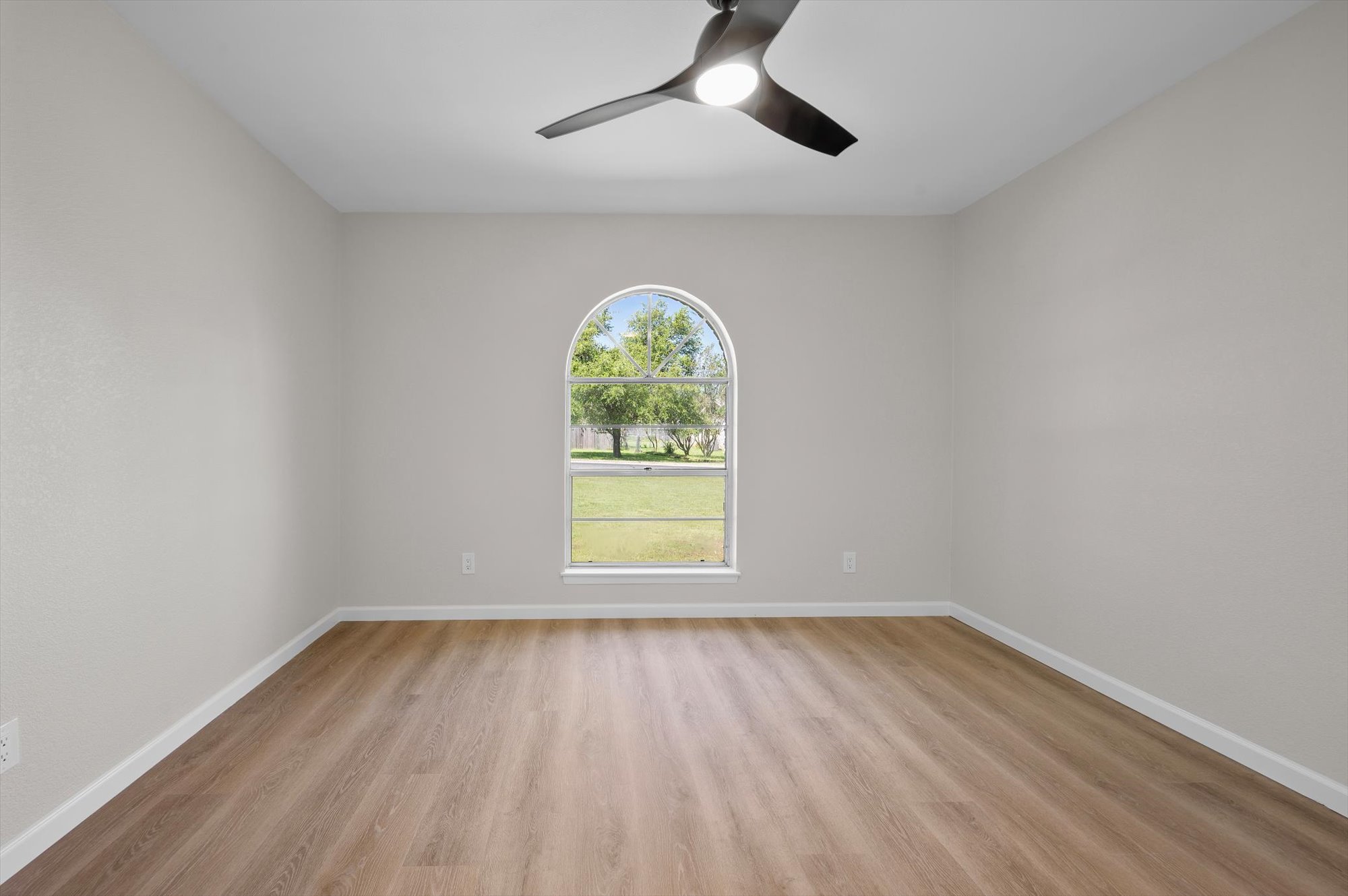 109 Woodland Road Georgetown, TX 78628 - Photo 29 of 40 A graceful arched window illuminates this pristine room, featuring sleek flooring and a contemporary ceiling fan.