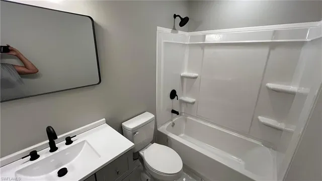 a white toilet sitting next to a sink and vanity