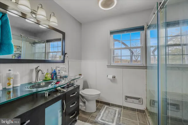 a bathroom with a granite countertop sink a toilet and a shower