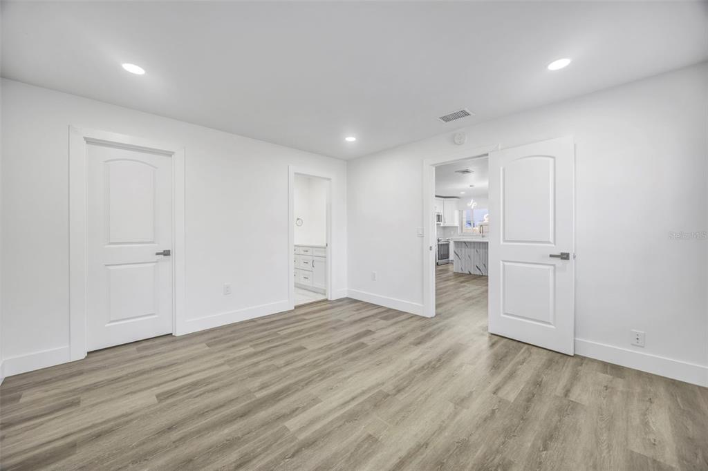 11728 Raintree Drive Temple Terrace, FL 33617 - Photo 16 of 41 a view of an empty room with wooden floor and a kitchen