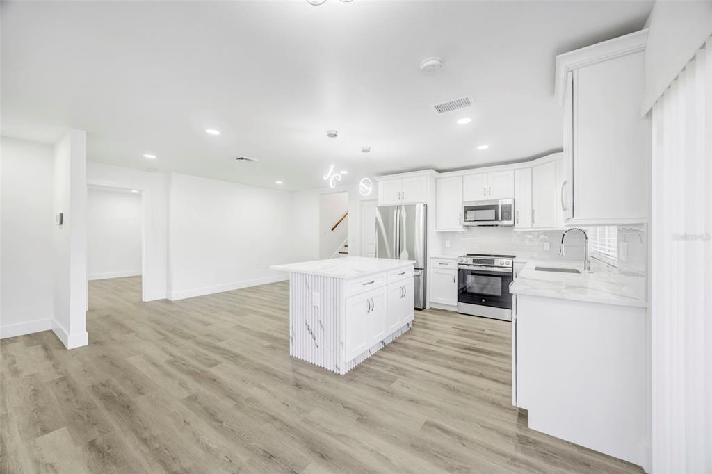 11728 Raintree Drive Temple Terrace, FL 33617 - Photo 7 of 41 a large white kitchen with wooden floor and stainless steel appliances