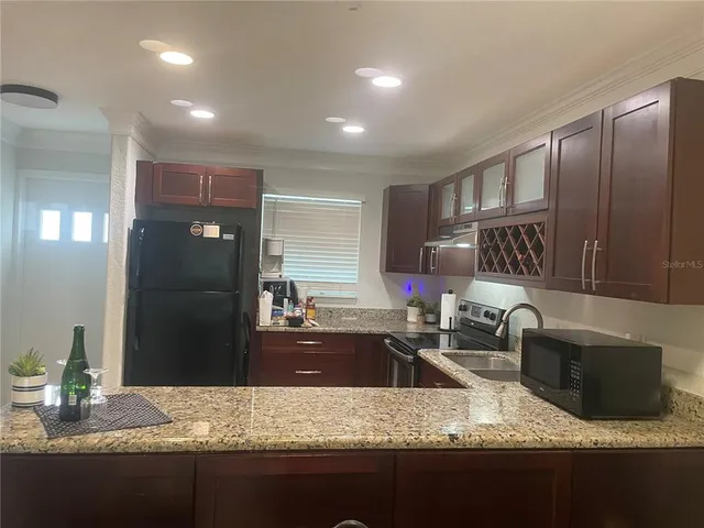 an empty room with kitchen and chandelier fan
