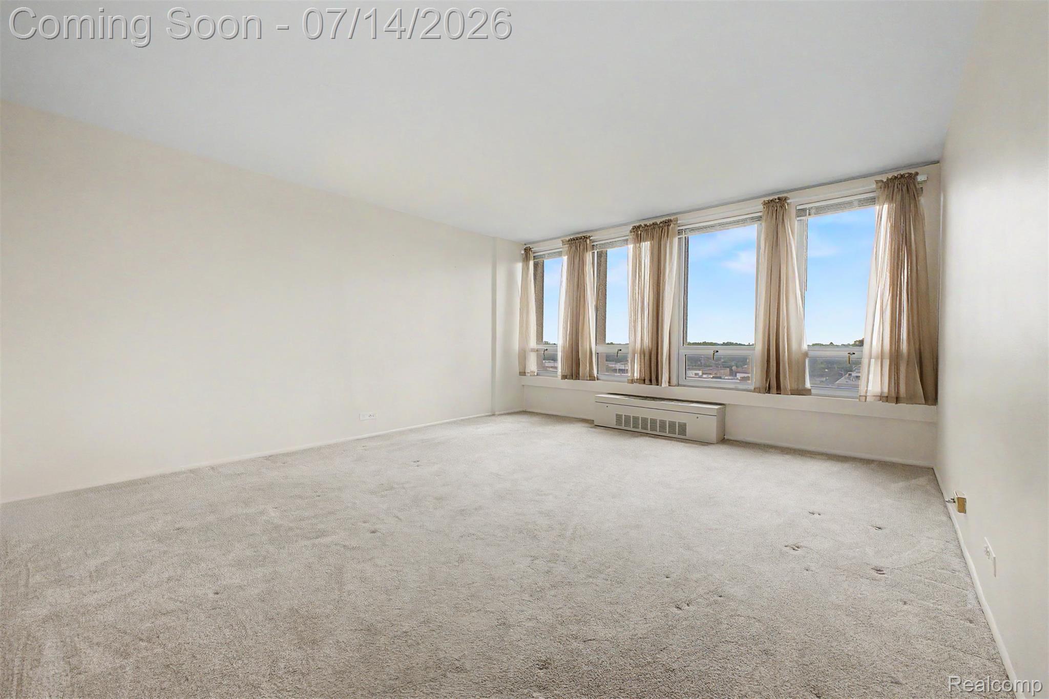 22700 Garrison Street, Unit 707 Dearborn, MI 48124 - Photo 3 of 22 Bright interior space featuring a wall of multiple windows, neutral carpeting, and light-toned walls