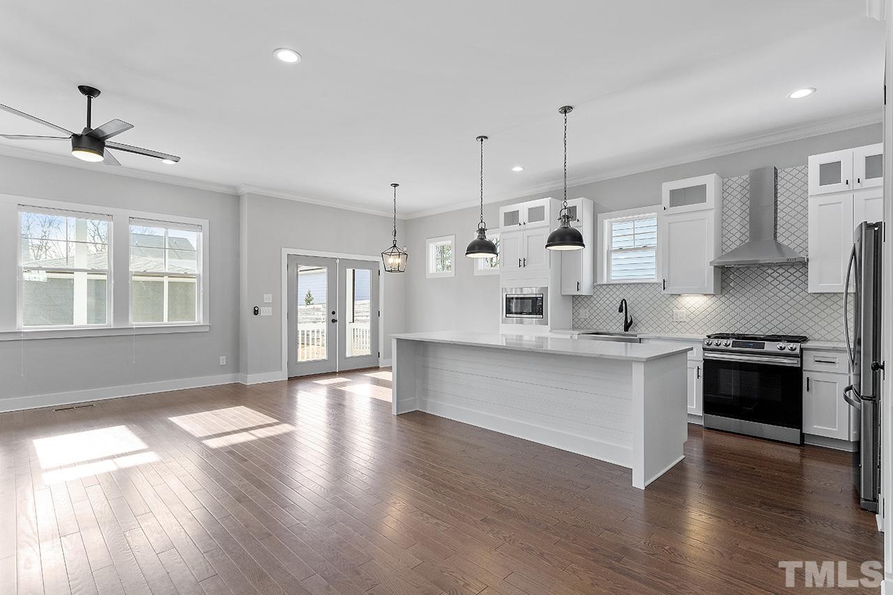 2320.5 Milburnie Road Raleigh, NC 27610 - Photo 7 of 32 a large kitchen with granite countertop a stove top oven a sink a dining table and chairs with wooden floor