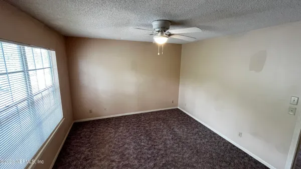 an empty room with a chandelier fan and windows