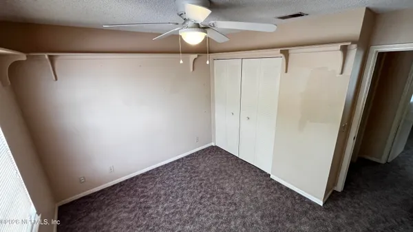 an empty room with windows and fan