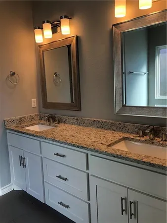 a bathroom with a granite countertop sink vanity and mirror