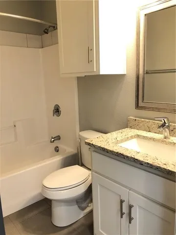 a bathroom with a granite countertop toilet sink and mirror