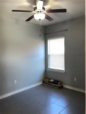 an empty room with a ceiling fan and window