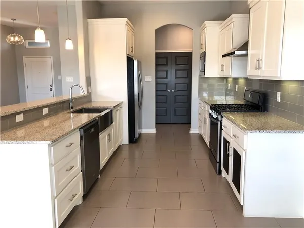 a kitchen with stainless steel appliances granite countertop a sink a stove and a refrigerator