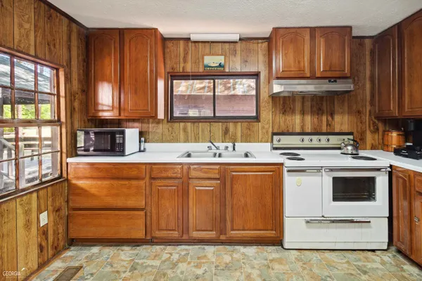 a kitchen with granite countertop a refrigerator and a stove top oven